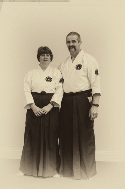 Sensei Joanne Penk and Sensei David Penk standing side by side in white gi and dark hakama
