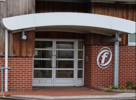 The entrance to Hassocks Sports Centre: red brick, timber cladding and a white curved canopy