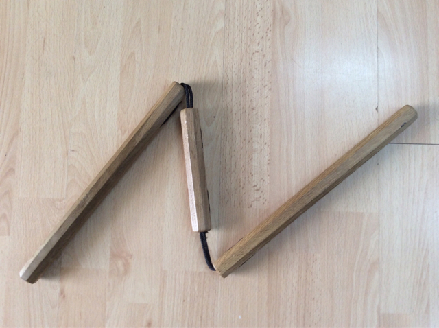 A pair of wooden nunchaku laid on a pale wooden floor